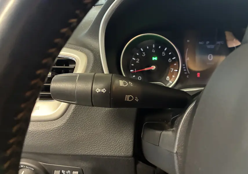 Gros plan sur la commande des clignotants et phares du Jeep Compass ivoire, avec tableau de bord partiellement visible.