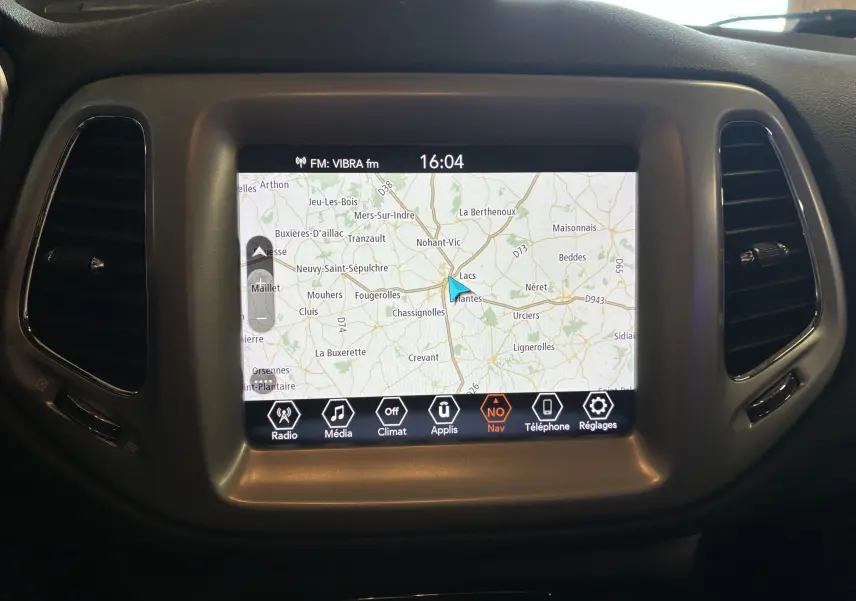 Écran tactile central du tableau de bord du Jeep Compass ivoire, affichant la navigation GPS en mode carte.