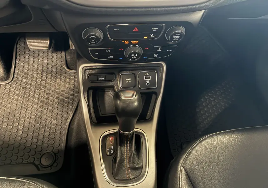 Vue rapprochée de la console centrale du Jeep Compass ivoire 2021, avec levier de vitesses automatique et commandes climatisation.