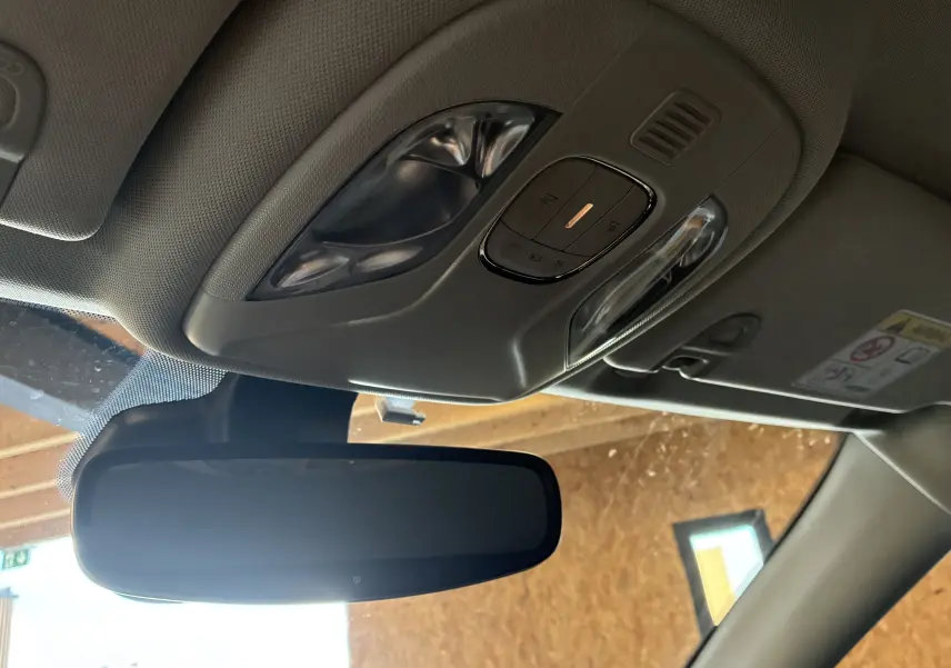 Vue intérieure du plafonnier et rétroviseur intérieur noir du Jeep Compass ivoire, avec commandes d’éclairage intégrées.