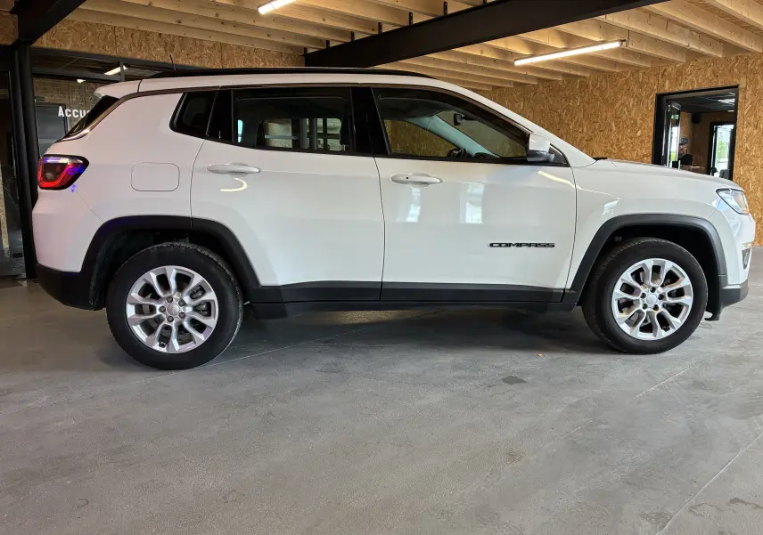 Vue de profil côté gauche d’un Jeep Compass ivoire avec jantes alu et logo "Compass" sur la porte arrière.