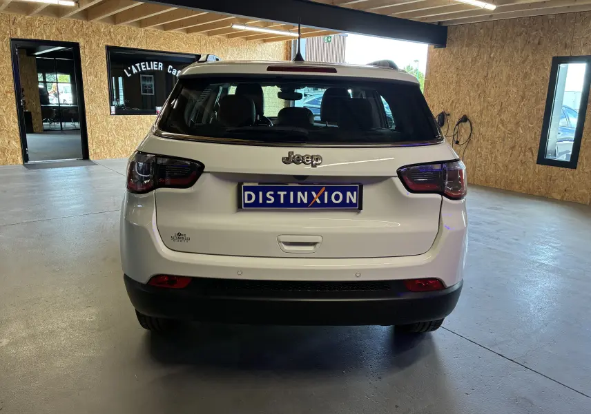 Vue arrière d'un Jeep Compass ivoire 2021 avec feux LED et lunette arrière dégivrante en intérieur.