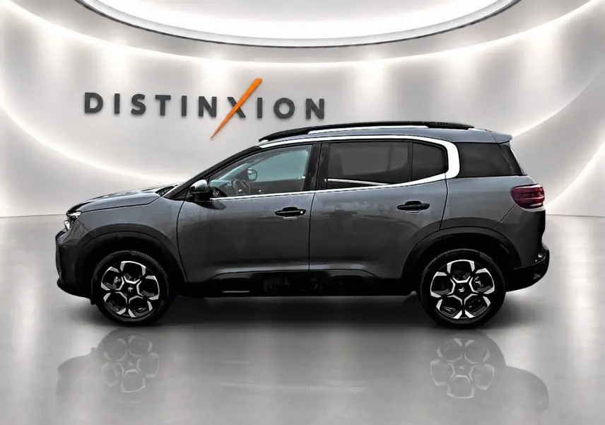 Vue latérale droite d'un Citroën C5 Aircross gris 2025 avec jantes alu et barres de toit noires.