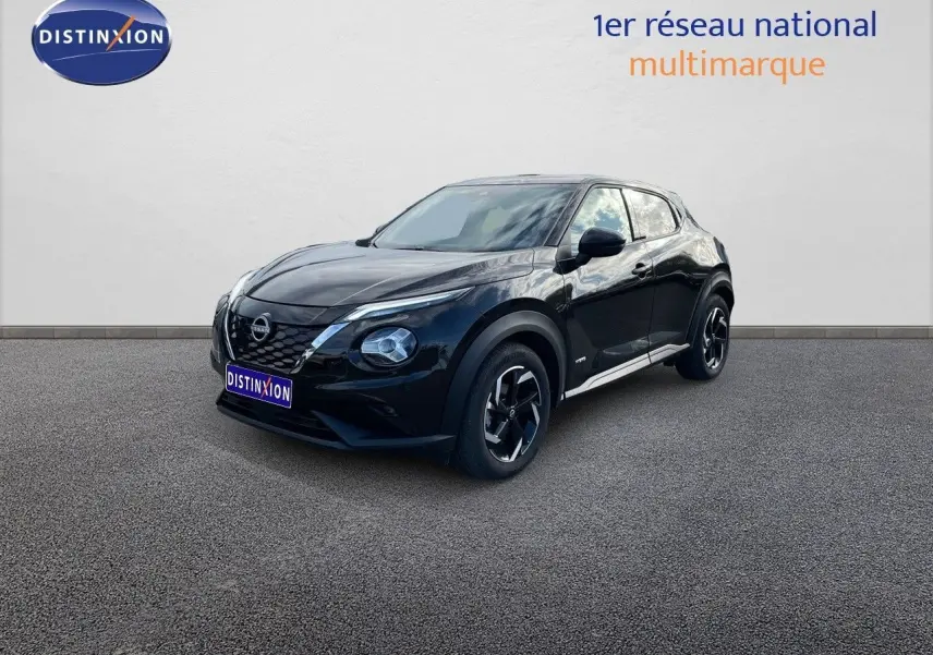 Nissan Juke 2024 noir métal en 3/4 avant droit, avec jantes bi-ton et calandre distinctive V-Motion.