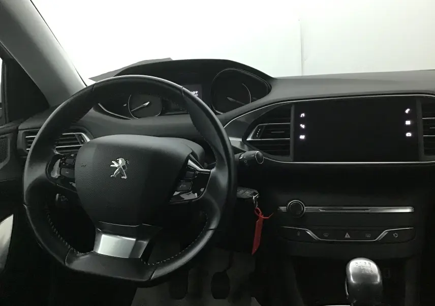 Intérieur noir de la Peugeot 308 SW 2018, vue du tableau de bord avec volant et levier de vitesse manuel.