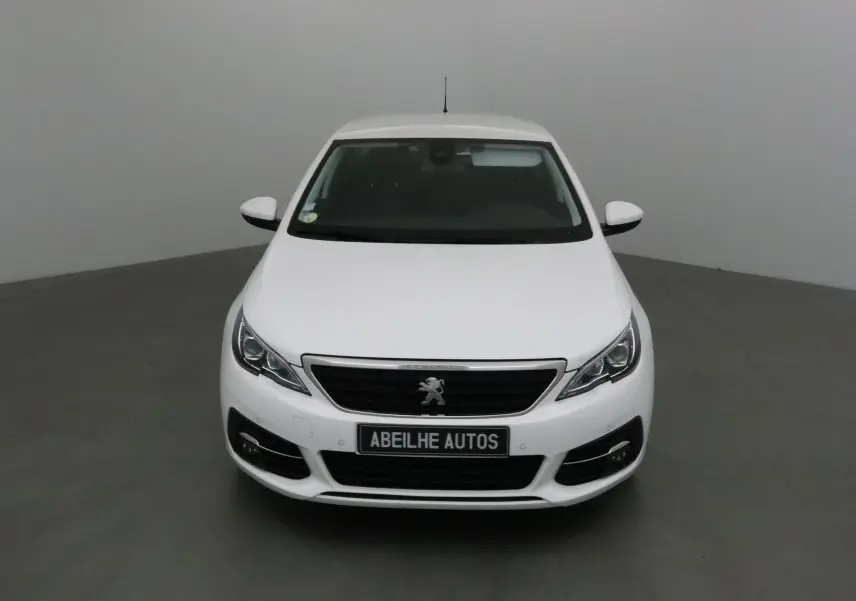 Vue frontale d'une Peugeot 308 SW blanche de 2018 avec calandre noire et logo lion visible.
