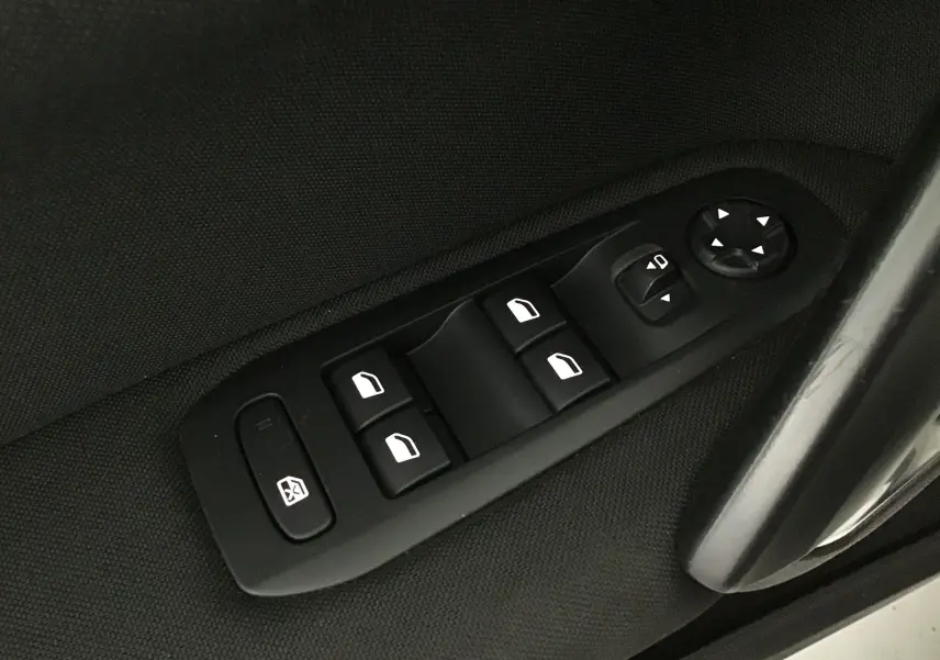 Commande des vitres électriques et réglage des rétroviseurs sur la porte côté gauche d'une Peugeot 308 SW blanche.