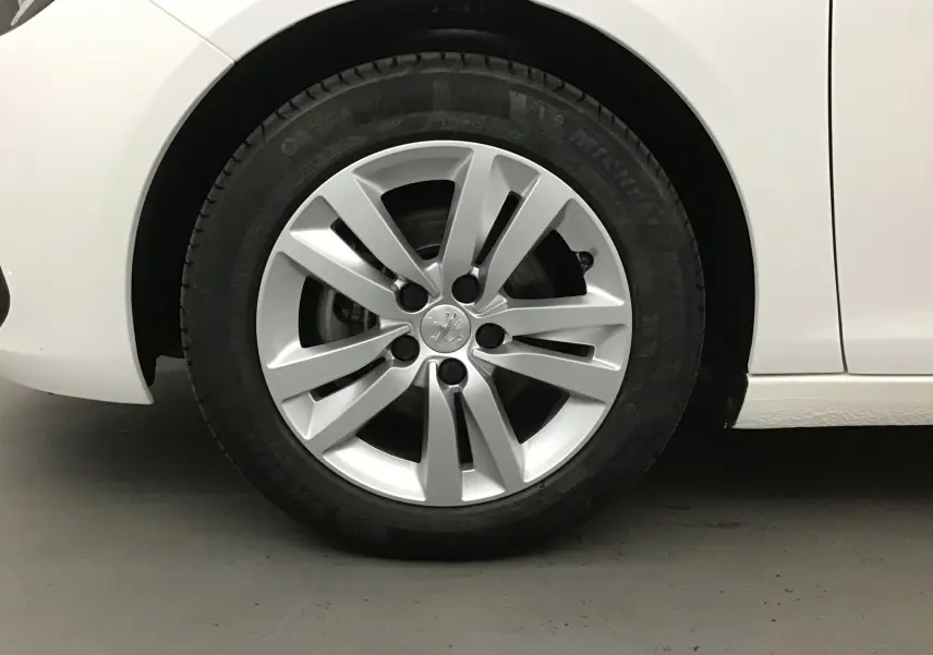 Gros plan sur la roue avant gauche d'une Peugeot 308 SW blanche de 2018 avec jante alliage 16 pouces.