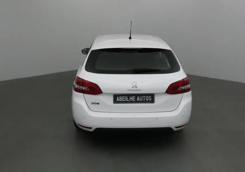 Vue arrière d'une Peugeot 308 SW blanche de 2018 avec feux arrière rouges et plaque Abeilhe Autos.