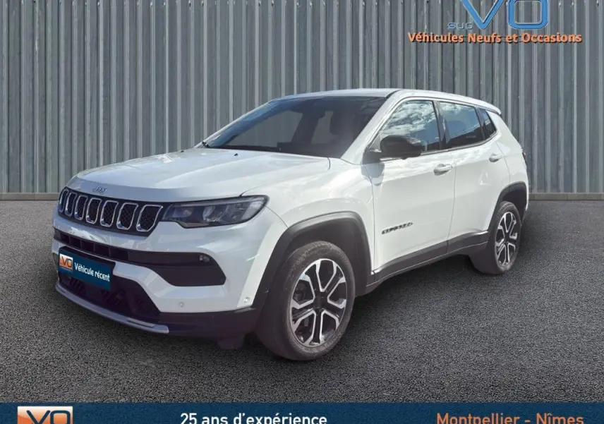 Jeep Compass blanc en 3/4 avant droit, jantes alliage 18 pouces et calandre distinctive sur fond urbain.