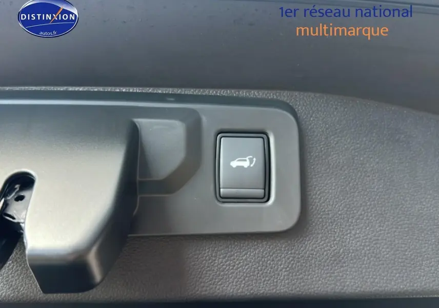 Bouton d'ouverture électrique du coffre sur panneau intérieur gris foncé du Renault Austral bleu.