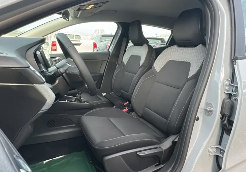 Vue intérieure côté conducteur de la Renault Clio gris rafale 2025, sièges avant en tissu noir et gris, volant multifonctions.