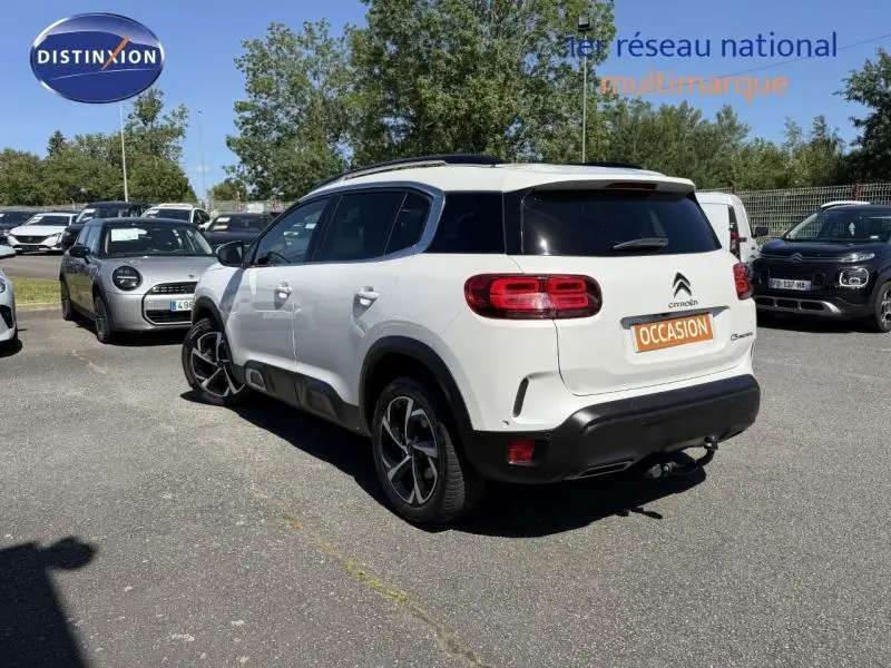 Vue 3/4 arrière droite d'un Citroën C5 Aircross blanc avec feux arrière LED et attelage visible en extérieur.