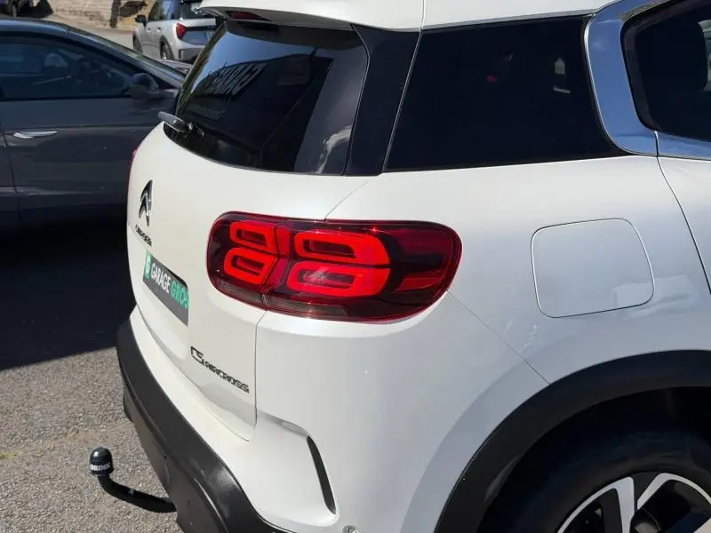 Vue arrière côté droit d'une Citroën C5 Aircross blanche avec feux arrière LED et attelage de remorque visible.