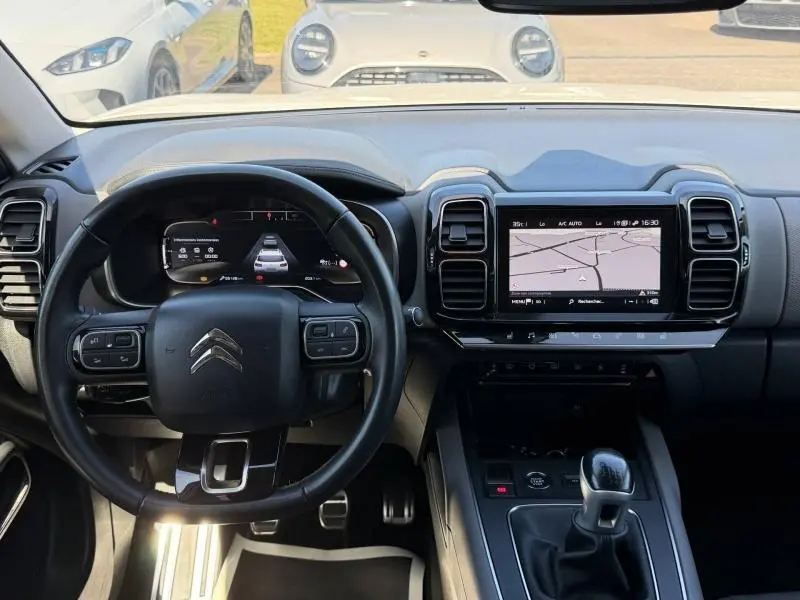 Vue intérieure centrée sur le tableau de bord et volant cuir noir du Citroën C5 Aircross gris, avec écran tactile et levier de vitesses manuel.
