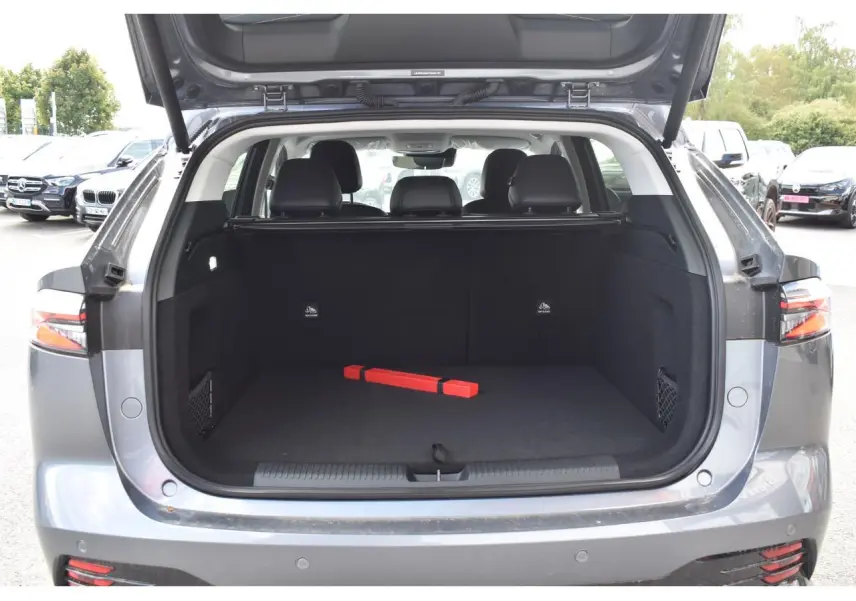 Coffre ouvert du MG MOTOR EHS 1.5 Hybrid+ gris 2026, vue arrière montrant l’espace de chargement et les sièges noirs.