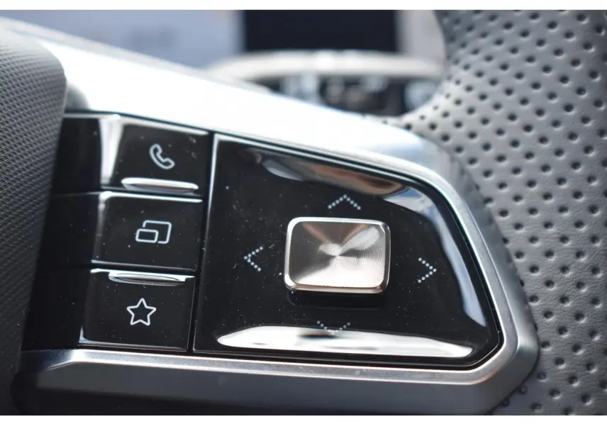 Gros plan sur les commandes multifonctions du volant perforé du MG Motor EHS gris, version hybride 2026.