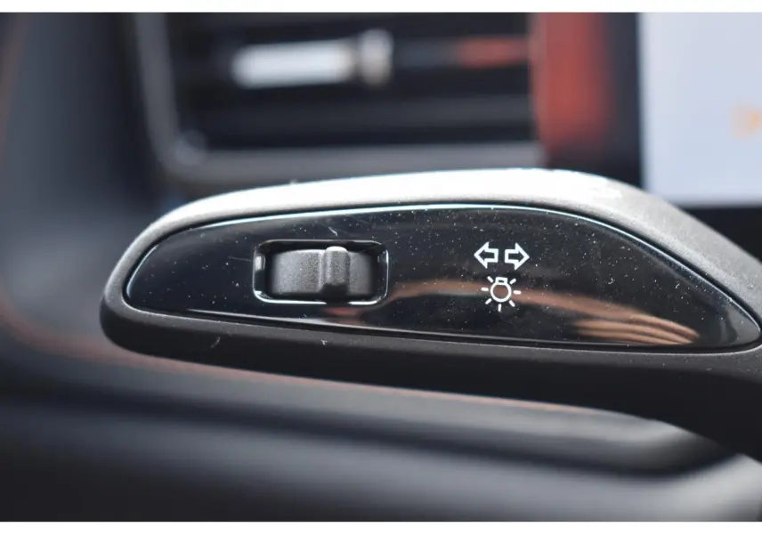 Gros plan sur le bouton de réglage des feux et clignotants dans l’habitacle du MG MOTOR EHS gris 2026.