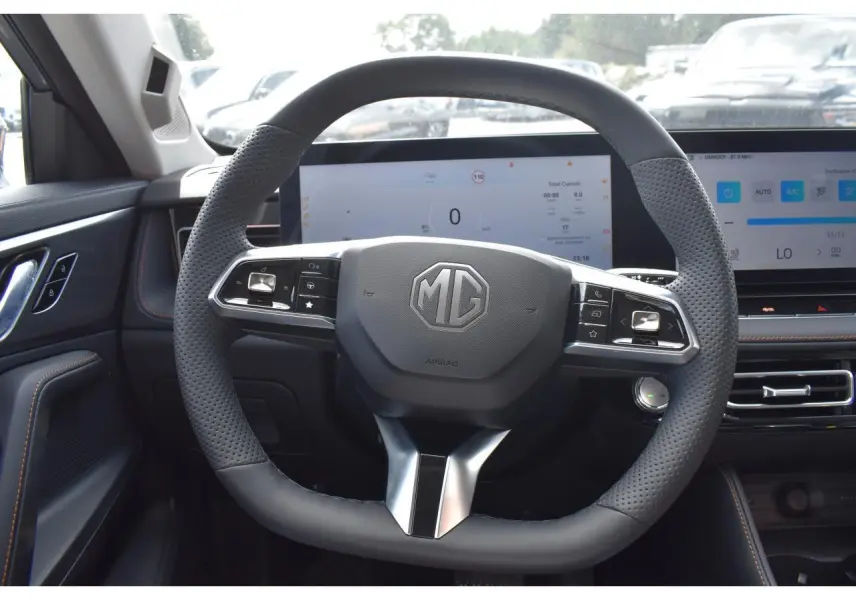 Vue intérieure centrée sur le volant perforé du MG Motor EHS 1.5 Hybrid+ 224 ch, avec tableau de bord numérique.