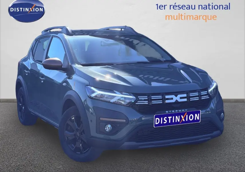 Vue 3/4 avant d'une Dacia Sandero Stepway 2025 en kaki lichen avec jantes noires et barres de toit.