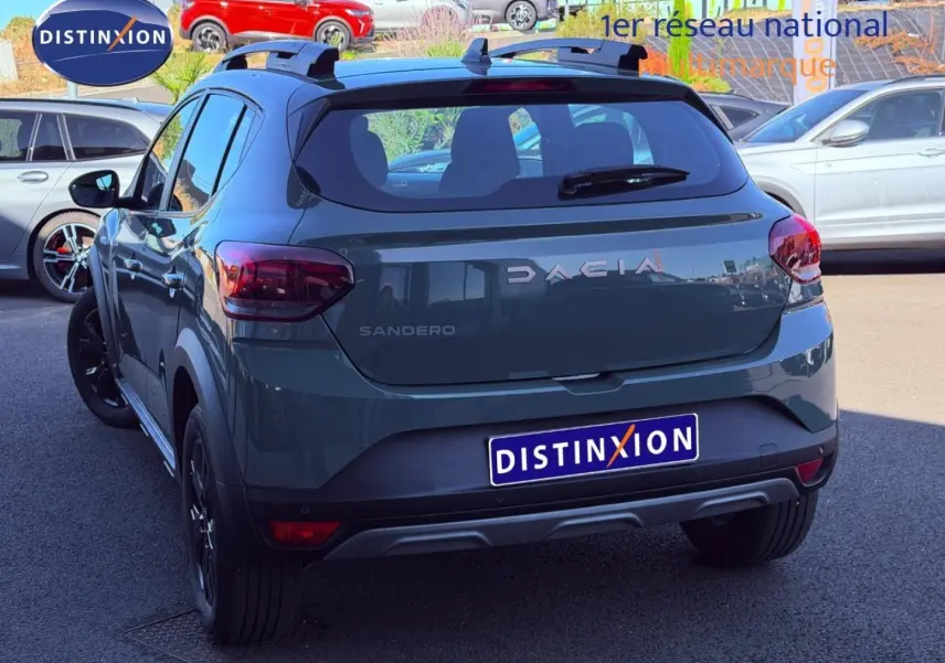 Vue 3/4 arrière d'une Dacia Sandero Stepway 2025 en kaki lichen avec barres de toit et jantes noires.
