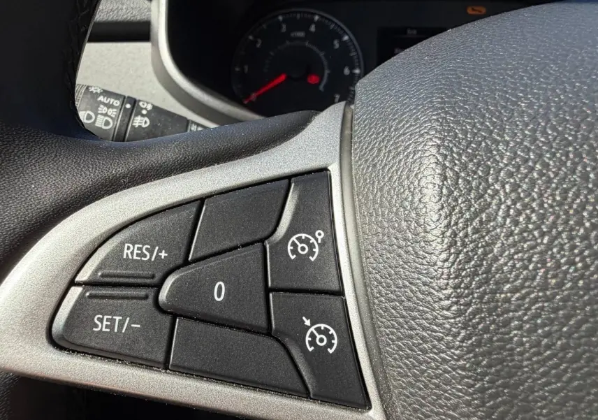 Gros plan sur les commandes de régulateur de vitesse au volant d’une Dacia Sandero 2025, intérieur noir.