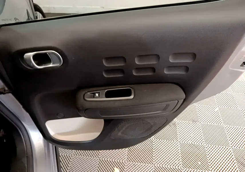 Gros plan sur la porte avant gauche gris clair de la Citroën C3 2019 avec poignée chromée et haut-parleur intégré.