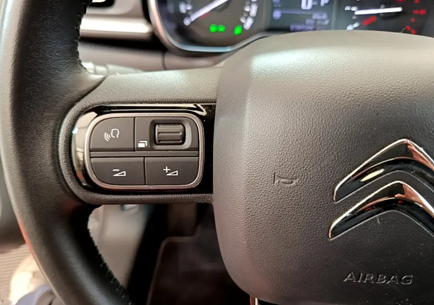Gros plan sur le volant cuir noir de la Citroën C3 2019 avec commandes audio intégrées côté gauche.