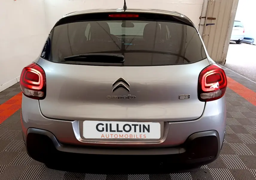Vue arrière d'une Citroën C3 gris clair avec feux arrière allumés dans un garage intérieur.
