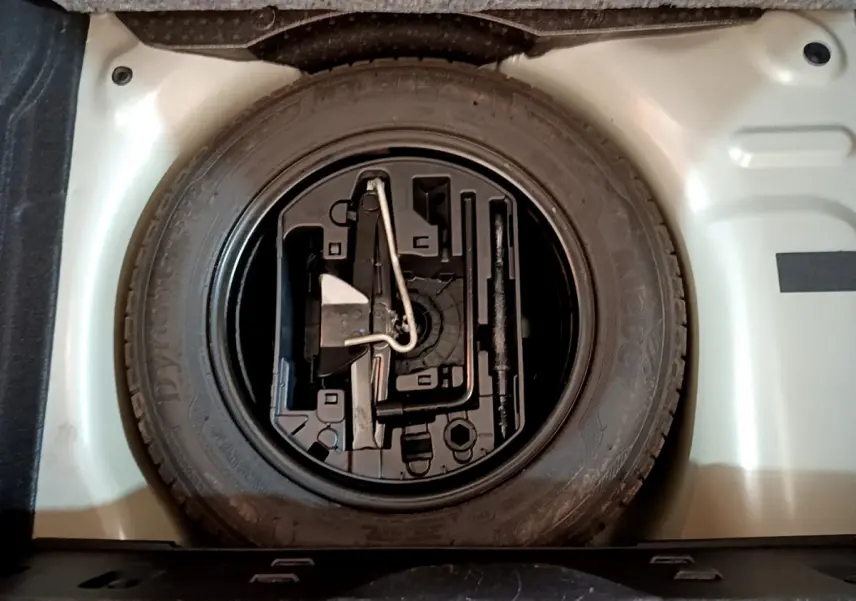 Gros plan sur la roue de secours et son rangement dans le coffre gris clair d'une Citroën C3 2019 PureTech Shine Business.