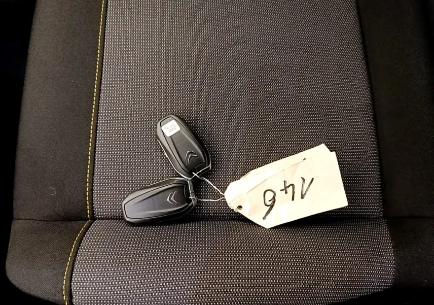 Gros plan sur deux clés noires Citroën posées sur un siège gris foncé avec surpiqûres jaunes.