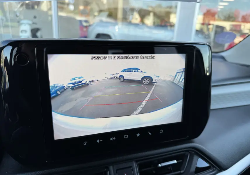 Écran de caméra de recul affichant un parking avec une Suzuki Swift 2024 blanc/gris vue de l'arrière.