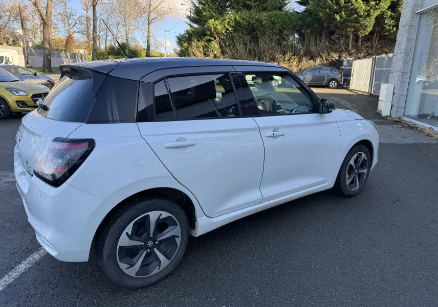 Suzuki Swift 1.2 Dualjet Pack Auto Hybrid blanc et gris vue 3/4 arrière côté droit, toit noir contrasté.