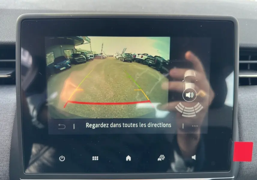 Écran tactile intérieur montrant la caméra de recul de la Renault Clio gris schiste, avec lignes de guidage colorées.