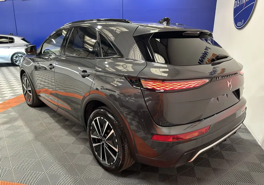 Vue 3/4 arrière droite du DS7 gris titane avec feux arrière LED et jantes alliage bicolores en showroom.
