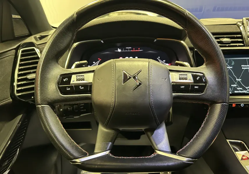 Vue rapprochée du volant en cuir perforé noir avec logo DS, tableau de bord numérique et écran tactile visible à droite.