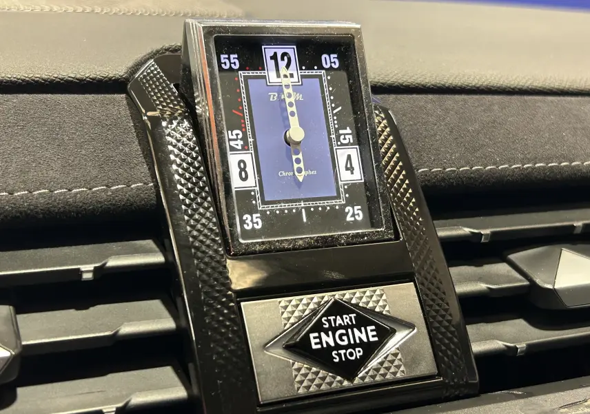 Gros plan sur l’horloge analogique et bouton start/stop du tableau de bord du DS7 gris titane 2024.