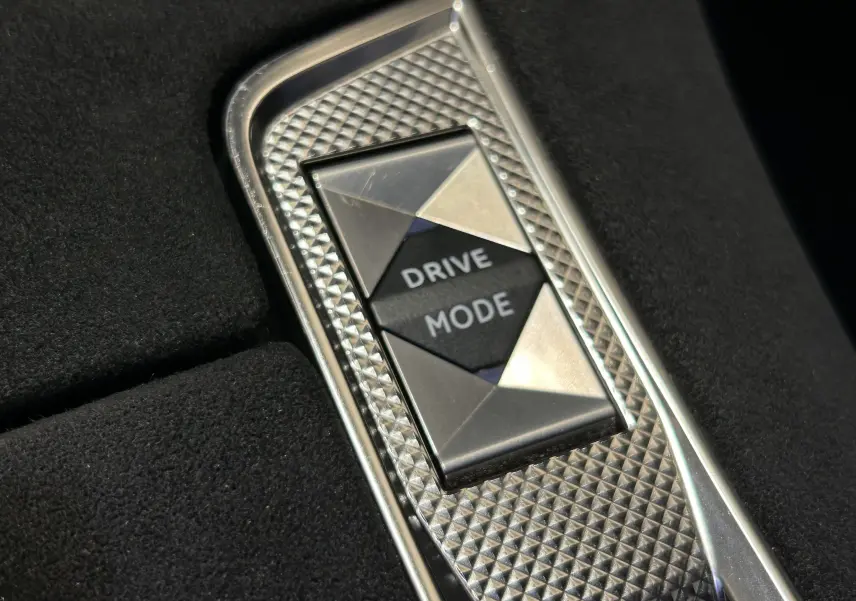 Gros plan sur le bouton Drive Mode avec finition métal texturée dans l’habitacle sombre du DS7 Gris Titane 2024.