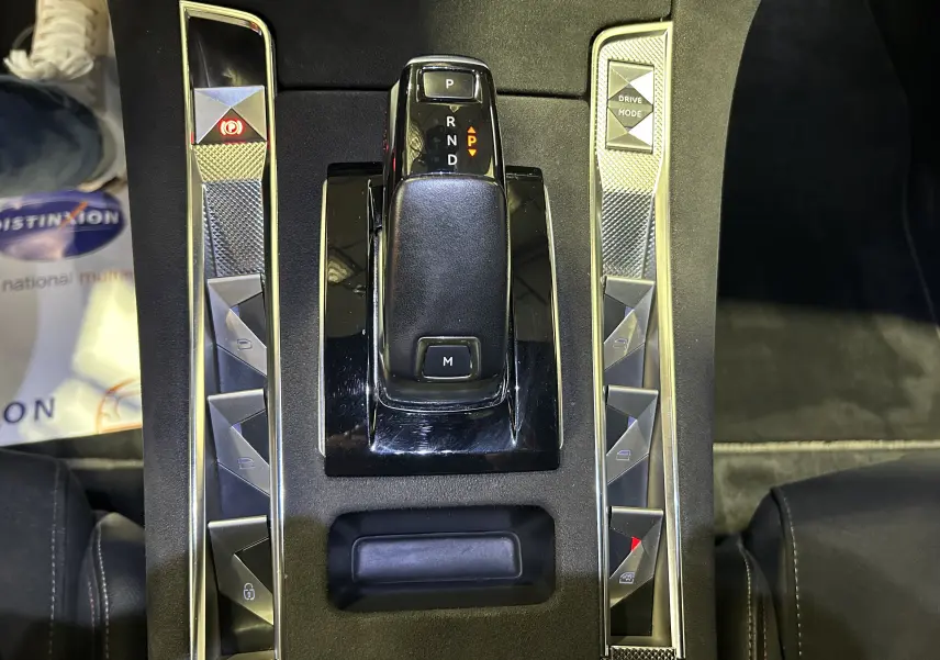 Gros plan sur la console centrale noire du DS7 2024 avec levier de vitesses automatique et boutons triangulaires argentés.