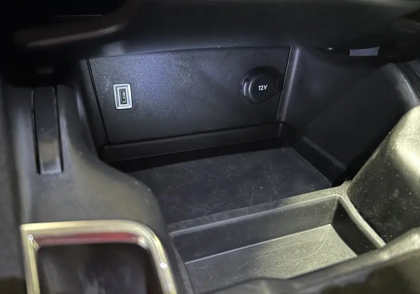 Gros plan sur la prise 12V et port USB dans le rangement central noir du DS7 gris titane 2024.