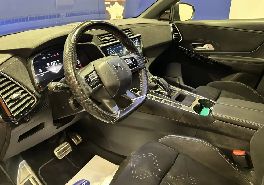 Vue intérieure côté conducteur du DS7 2024, montrant le volant, tableau de bord numérique et sièges en cuir noir.