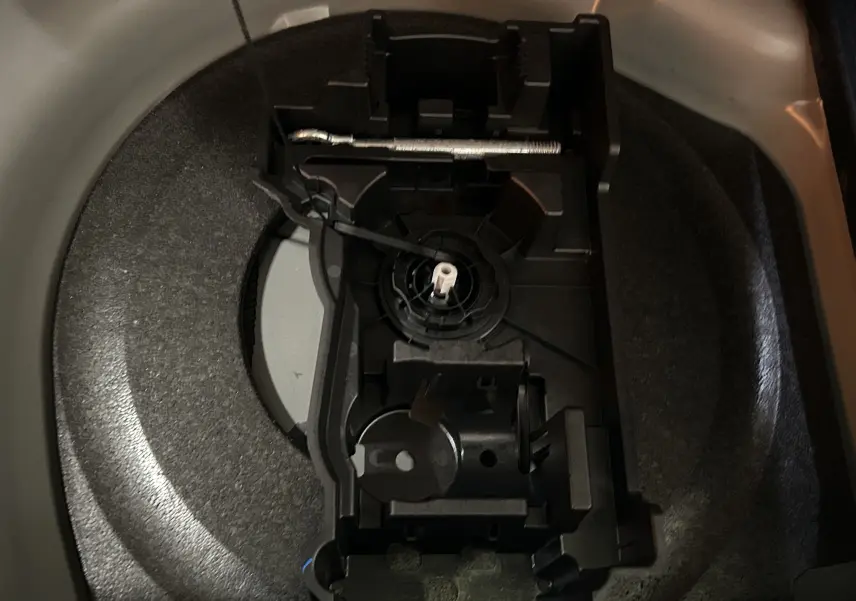 Gros plan sur le rangement de la roue de secours dans le coffre d’une DS7 gris titane, sans roue visible.