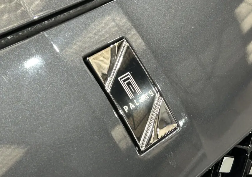 Gros plan sur l'emblème Pallas en chrome sur la calandre d'une DS7 gris titane 2024.