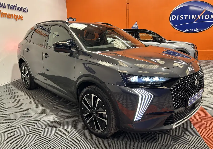 DS7 BlueHDi 130 gris titane en 3/4 avant droit, avec signature lumineuse LED distinctive et jantes noires bicolores.