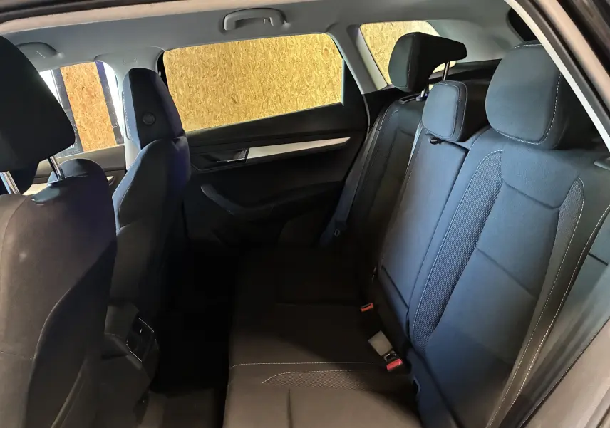 Vue intérieure côté droit des sièges arrière noirs du Skoda Karoq 2024 avec appuie-têtes et garnitures de porte sombres.