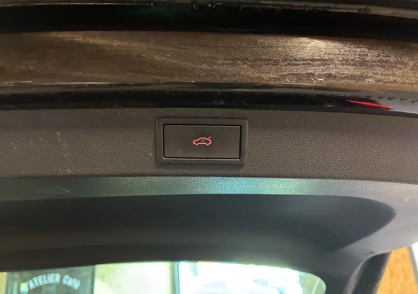 Bouton d'ouverture électrique du coffre sur la garniture intérieure noire du hayon d'un Skoda Karoq noir.