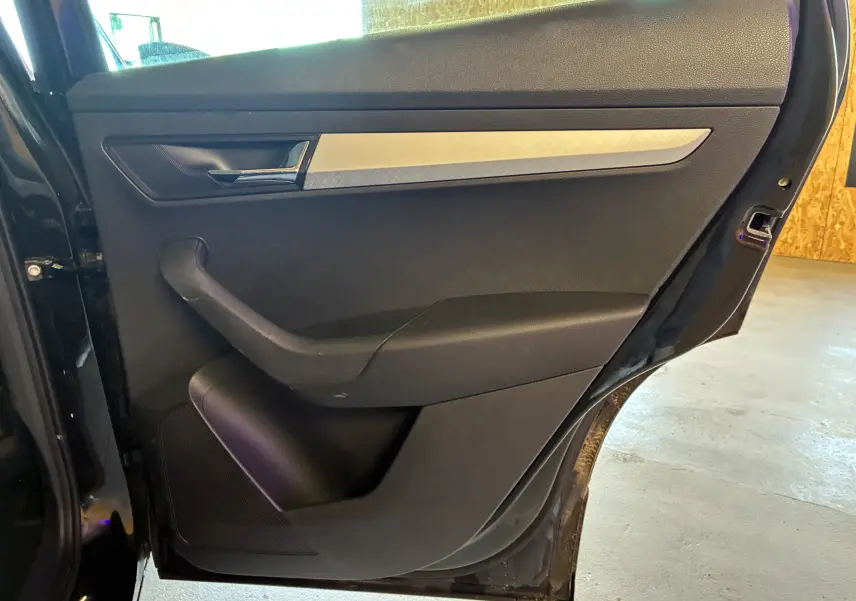 Vue intérieure de la porte arrière droite noire du Skoda Karoq 2024 avec poignée chromée et insert décoratif argenté.