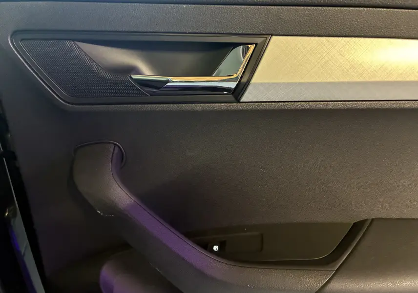 Poignée de porte intérieure chromée et garniture noire avec insert décoratif argenté dans une Skoda Karoq 2024.