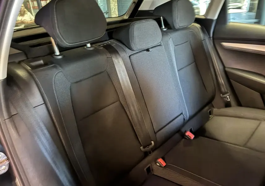 Vue intérieure arrière du Skoda Karoq 2024 noir, montrant la banquette arrière en tissu avec appuie-têtes et ceintures de sécurité.