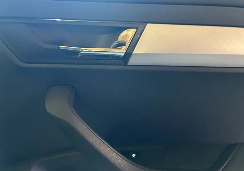 Détail de la poignée intérieure chromée et insert argenté sur la porte côté gauche d’un Skoda Karoq noir 2024.